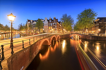 Dusk lights on typical buildings and bridges reflected in a typical canal, Amsterdam, Holland (The Netherlands), Europe