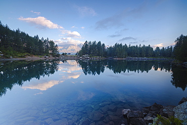 Clouds and woods reflected in Lago Azzurro at dawn, Motta Madesimo, Spluga Valley, Sondrio, Valtellina, Lombardy, Italy, Europe