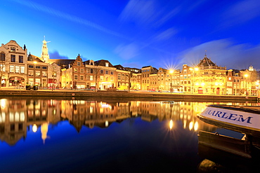 Dusk lights up typical houses reflected in a canal of the River Spaarne, Haarlem, North Holland, The Netherlands, Europe