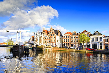 Blue sky and clouds on typical houses reflected in the canal of the River Spaarne, Haarlem, North Holland, The Netherlands, Europe