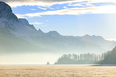 Mist at sunset on Lake Sils covered with snow, Maloja, Engadine, Canton of Graubunden, Switzerland, Europe