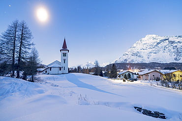 Lights of dusk on Chiesa Bianca and alpine village covered with snow, Maloja Pass, Engadine, Canton of Graubunden, Switzerland, Europe