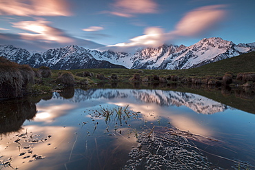 Snowy peaks and pink clouds reflected in water at dawn, Tombal, Soglio, Bregaglia Valley, canton of Graubunden, Switzerland, Europe