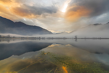 Mountains reflected in water at dawn shrouded by mist, Pozzo di Riva Novate, Mezzola, Chiavenna Valley, Lombardy, Italy, Europe