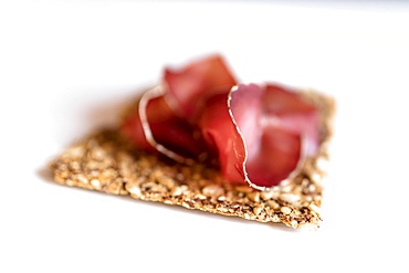 Close up of Bresaola, the typical raw beef cured by salting and air-drying, on white background, Valtellina, Lombardy, Italy, Europe