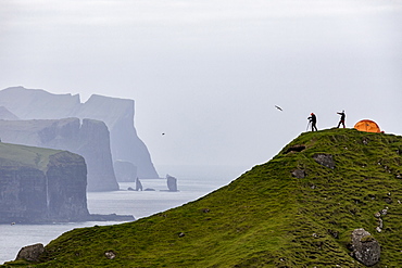 Hikers and tent on cliffs, Kalsoy Island, Faroe Islands, Denmark, Europe