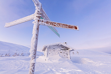 Frozen signage and wood hut, Pallas-Yllastunturi National Park, Muonio, Lapland, Finland, Europe