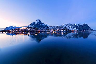 Overview of village and snowy peaks at dusk, Reine Bay, Lofoten Islands, Nordland, Norway, Europe