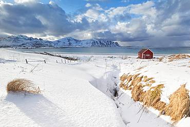 Wood cabin on sand beach covered with snow, Ramberg, Flakstad municipality, Lofoten Islands, Nordland, Norway, Europe