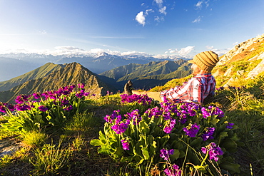 Man lying on top of Monte Azzarini looks towards Monte Disgrazia and Monte Pedena, Albaredo Valley, Orobie Alps, Lombardy, Italy, Europe