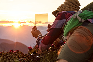 Man at sunset with graduated photography filters in his hand, San Marco Pass, Orobie Alps, Bergamo province, Lombardy, Italy, Europe