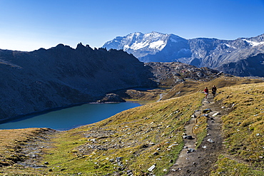 Hikers walking on the Colle del Nivolet beside Rossett Lake (Lago Rossett), Gran Paradiso National Park, Alpi Graie (Graian Alps), Italy, Europe 