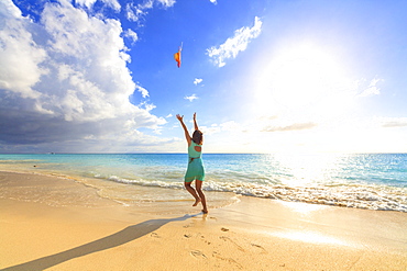 Woman on seashore throws the hat up in the air, Ffryes Beach, Antigua, Antigua and Barbuda, Leeward Islands, West Indies, Caribbean, Central America