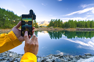 Hiker snaps photos with smartphone, Lago Azzurro, Spluga Valley, Sondrio province, Valtellina, Lombardy, Italy, Europe