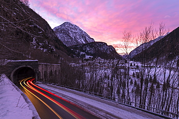 Car trail lights on the icy road at dawn, Campodolcino, Spluga valley, Sondrio province, Valtellina, Lombardy, Italy, Europe