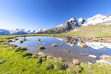 Snowy peaks reflected in the alpine lake, Motta di Olano, Valgerola, Valtellina, Sondrio province, Lombardy, Italy, Europe