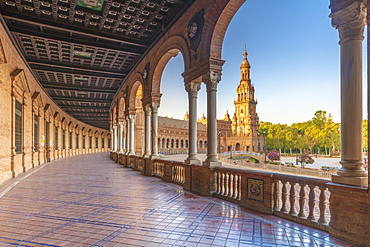 Sunrise on the old tower seen from colonnade of the semi-circular portico, Plaza de Espana, Seville, Andalusia, Spain, Europe