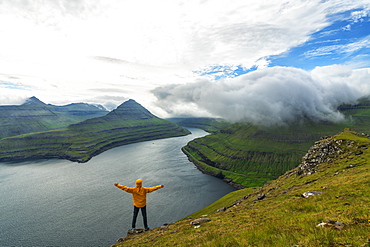 Man with open arms rejoices looking to the fjords, Funningur, Eysturoy island, Faroe Islands, Denmark, Europe