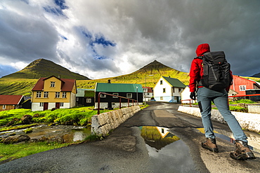 Hiker in the traditional village of Gjogv, Eysturoy island, Faroe Islands, Denmark, Europe