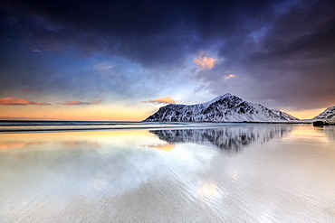 Sunset on Skagsanden beach surrounded by snow covered mountains reflected in the cold sea, Flakstad, Lofoten Islands, Arctic, Norway, Scandinavia, Europe