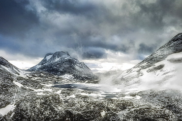 Storm clouds over Olaskarsvatnet lake at feet of the snowcapped Olaskarstind mountain, Venjesdalen valley, Andalsnes, Norway, Scandinavia, Europe