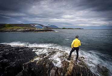 Hiker admiring the Atlantic Road from cliffs washed by waves, More og Romsdal county, Norway, Scandinavia, Europe