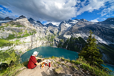 Hiker cooking food on camping stove high up above Oeschinensee lake, Bernese Oberland, Kandersteg, Canton of Bern, Switzerland, Europe