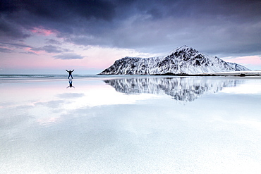 Sunset and hiker on Skagsanden beach surrounded by snow covered mountains, Flakstad, Lofoten Islands, Arctic, Norway, Scandinavia, Europe