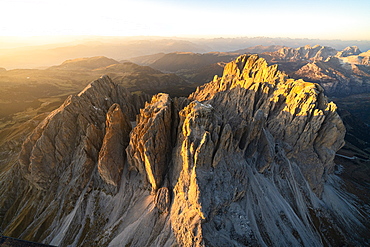 Aerial view of Sassolungo and Sassopiatto lit by the warm autumn sunset, Val Gardena, Val di Fassa, Dolomites, South Tyrol, Italy, Europe