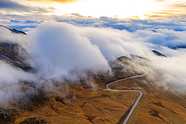 Aerial view by drone of fog over scenic road crossing Giau Pass in a sea of clouds at sunset, Dolomites, Belluno province, Veneto, Italy, Europe