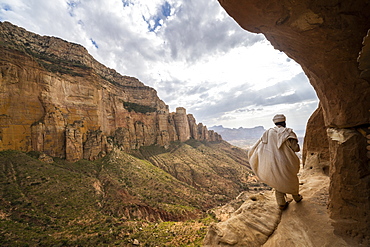 Rear view of priest walking on access trail to the rock-hewn Abuna Yemata Guh church, Gheralta Mountains, Tigray region, Ethiopia, Africa