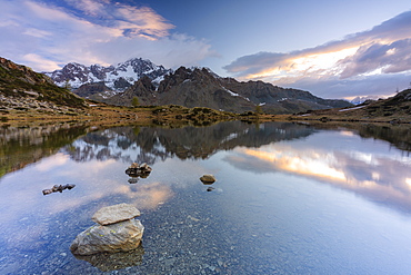 Sunrise lit the rocky peak of Monte Disgrazia mirrored in the clear water of lake Zana, Valmalenco, Valtellina, Lombardy, Italy, Europe