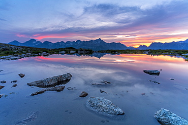 Burning sky at sunset on mountains mirrored in the pristine lake, Muottas Muragl, Engadine, canton of Graubunden, Switzerland, Europe