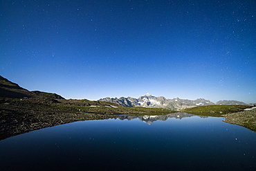 Starry sky over Galenstock mountain reflected in the pristine Mittleres Schwarziseeli lake, Furka Pass, Canton Uri, Switzerland, Europe