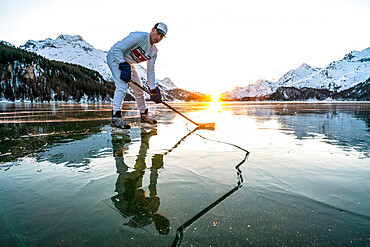 Front view of ice hockey player on cracked surface of frozen Lake Sils, Engadine, Graubunden canton, Switzerland, Europe