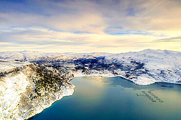 Aerial view of cloudy sky at sunset over fish farms and mountains along Altafjord in winter, Troms og Finnmark, Northern Norway, Scandinavia, Europe