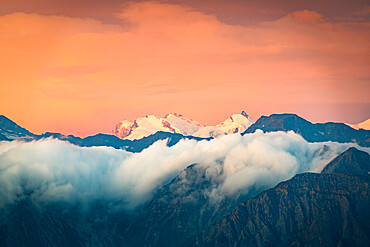 Burning sky at sunrise over the snow capped Monte Rosa surrounded by a sea of clouds, Valais canton, Switzerland, Europe