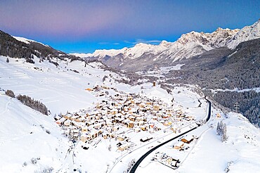 Mountain road crossing the village of Ardez covered with snow, aerial view, Engadine, Graubunden Canton, Switzerland, Europe