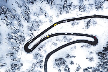 Aerial view of cars driving on narrow bends of mountain road in the snow, Switzerland, Europe