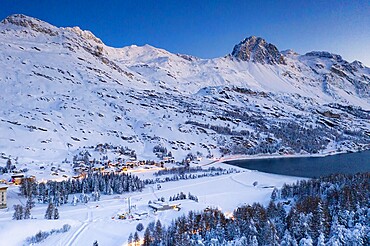 Dusk over the snow covered village of Maloja on shores of Lake Sils, Bregaglia, Engadine, Graubunden Canton, Switzerland, Europe