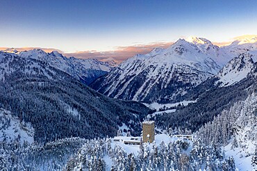 Sunrise on ancient Torre Del Belvedere tower and snowy woods, Maloja, Bregaglia, Engadine, Graubunden Canton, Switzerland, Europe