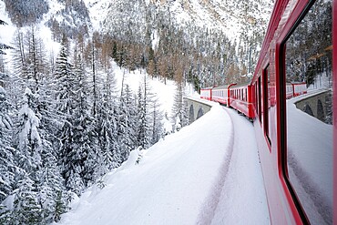 Bernina Express train in the alpine landscape covered with snow, Preda Bergun, Albula Valley, Graubunden Canton, Switzerland, Europe