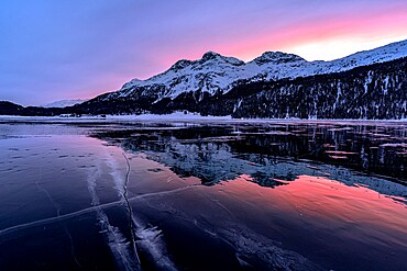 Winter sunrise on snowcapped mountains mirrored in the icy Lake Silvaplana, Maloja, Engadine, Graubunden canton, Switzerland, Europe