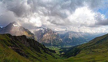 Panoramic of green valley surrounding Grindelwald and Bernese Alps lit by rainbow, First, Canton of Bern, Switzerland, Europe