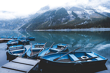 Row boats moored on shore of lake Oeschinensee on a foggy day, Bernese Oberland, Kandersteg, Bern canton, Switzerland, Eurpe