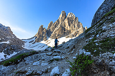 Hiker woman with backpack walking on path to Croda Dei Toni at sunrise, Val Fiscalina, Sesto Dolomites, South Tyrol, Italy, Europe