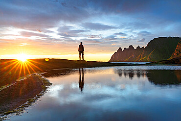 Silhouette of man standing on rocks watching the mountain peaks at sunset, Tungeneset viewpoint, Senja, Troms county, Norway, Scandinavia, Europe