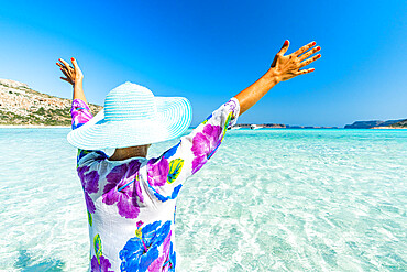 Cheerful woman with arms raised sunbathing in the clear sea, Crete, Greek Islands, Greece, Europe