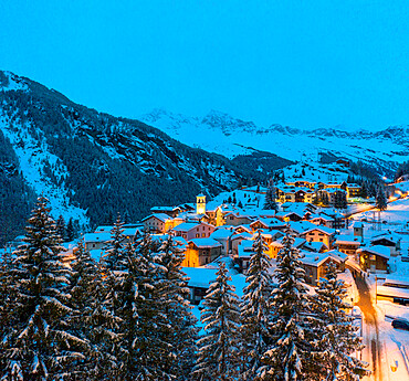 Blue dusk over snowcapped mountains and woods around the alpine huts of Pianazzo, Madesimo, Valle Spluga, Lombardy, Italy, Europe