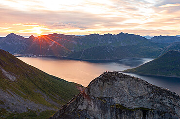 People admiring the sky at dawn standing on mountain top above the fjords, Senja island, Troms county, Norway, Scandinavia, Europe